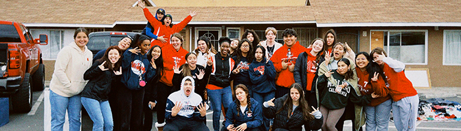 Group of spirited students outside a home wearing winter attire
